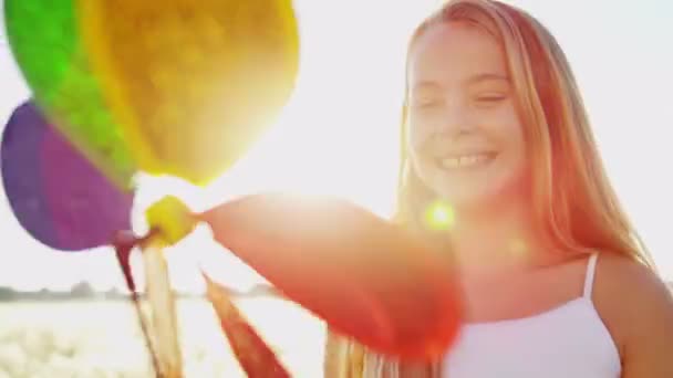 Menina ao ar livre jogando com colorido moinho de vento brinquedo — Vídeo de Stock