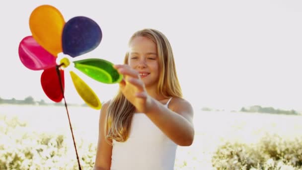 Chica al aire libre jugando con colorido molino de viento juguete — Vídeos de Stock