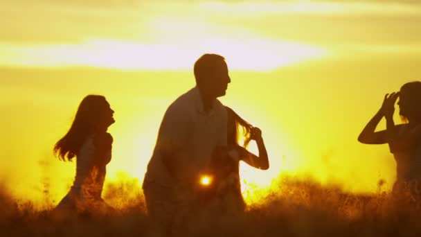 Pais com filhas no prado ao pôr do sol — Vídeo de Stock