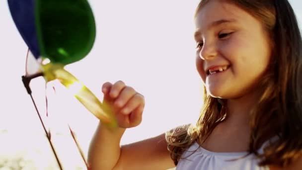 Девушка на открытом воздухе играет с красочной игрушкой ветряной мельницы — стоковое видео