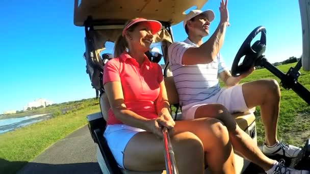 Casal de jogadores de golfe dirigindo carrinho de buggy — Vídeo de Stock