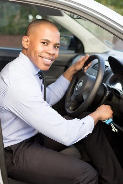 Joven negro hombre sonriendo mientras sentado en su coche — Foto de Stock