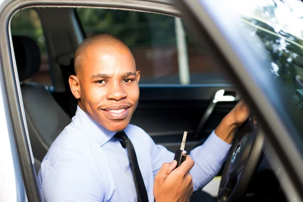 Homem negro jovem sorrindo enquanto sentado em seu carro — Fotografia de Stock