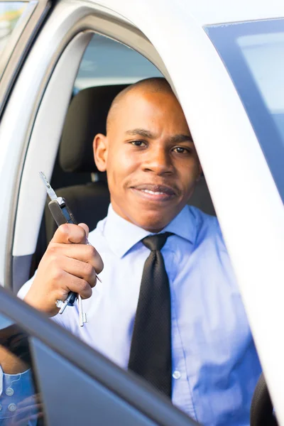 Jonge zwarte Man die lacht tijdens de vergadering in zijn auto Stockfoto