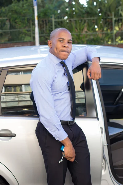 Fiatal fekete ember mosolyogva, miközben ül a kocsijában Stock Fotó