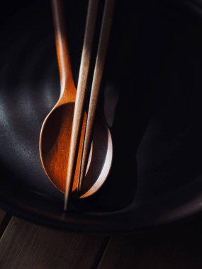 Tahta kaşık, yemek çubuğu ve porselen tabak.