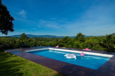 Arkadaki dağlara bakan tatil köyü yüzme havuzu ve sabahları parlak mavi gökyüzü..