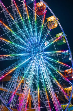 Geceleyin renkli gökkuşağı LED aydınlatma ve karanlık gökyüzüne karşı yolcu kabinleri olan canlı dönme dolap.