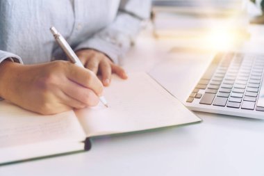 Kadın dizüstü bilgisayarını evde çalışırken ya da çalışırken planlı bir şekilde not alıyor. Eğitim sektörü yaşam tarzı kavramı.