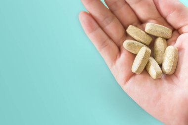 Alternatif organik tıp ya da bitkisel viatmin takviye kapsülü tabletinin telif alanı geçmişi olan kadın elinin en üst görüntüsü. Sağlıklı yeme yaşam tarzı kavramı.