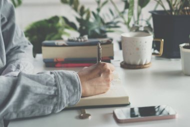 Kadın el yazısı küçük beyaz not defterine not alın, unutmayın ya da gelecek için liste planı yapın..