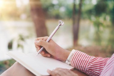 Kadın el yazısı küçük beyaz not defterine not alın, unutmayın ya da kamu parkında gelecek planı yapın..