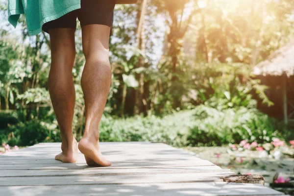 Woman is walking on small wood bridge to nature walk way with sunlight flare background.