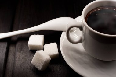 Siyah arka planda şekerli ve kaşıklı kahve fincanı. Kahve canlandırıcı ve tonik bir içecektir. Siyah arkaplanda izole et