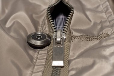 Fermuarlı kilit, gri renkli elbiselerin üzerine yakın plan çekimdir. Kilitli fermuar.