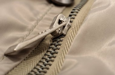 Fermuarlı kilit, gri renkli elbiselerin üzerine yakın plan çekimdir. Kilitli fermuar.