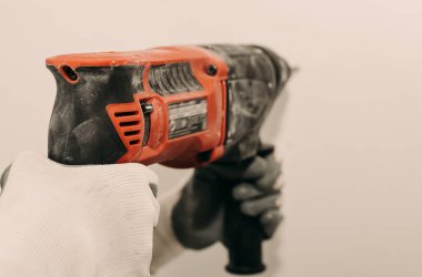 Elektrikli matkap. Elektrikli aletler. El, duvarda bir delik açmak için matkap kullanıyor. Tamir et. İnşaat