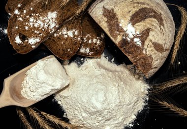 Ekmek, un, siyah arka planda buğday dikenleri. Un, pişirmenin ana bileşenidir..