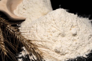 Un, siyah arka planda buğday dikenleri. Un, pişirmenin ana bileşenidir..