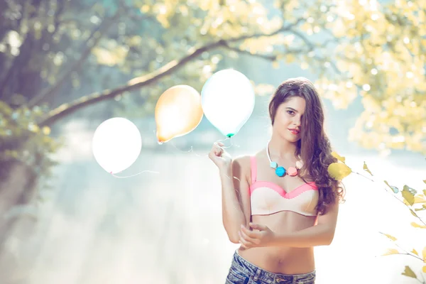 Chica con globos posando en la orilla del río en la mañana —  Fotos de Stock