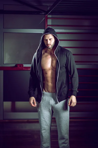 Man bär hoodie poserar i gym — Stockfoto