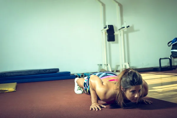 Flickan gör armhävningar i gym — Stockfoto