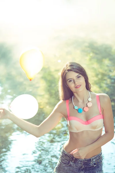 Chica con globos posando en la orilla del río en la mañana —  Fotos de Stock