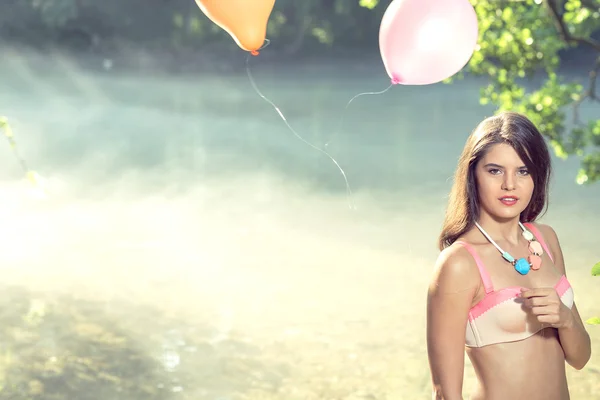 Fille avec des ballons posant au bord de la rivière le matin — Photo