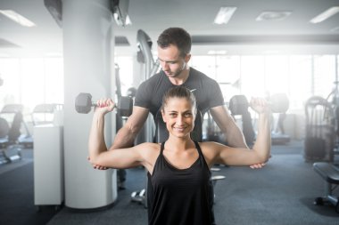 Kadın fitness antrenör yardımıyla yapıyor.
