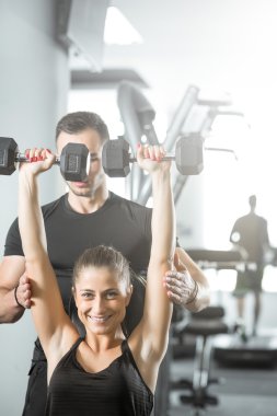 Kadın fitness antrenör yardımıyla yapıyor.