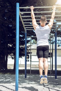 Kaslı adam pull-up egzersiz açık havada yapmak.