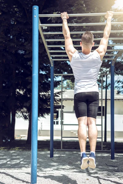 Homem muscular fazendo pull-ups exercício ao ar livre . — Fotografia de Stock