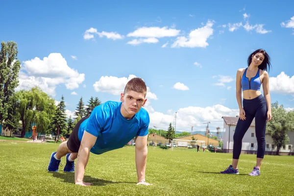 Young man doing push ups outdoor in grass. — ストック写真