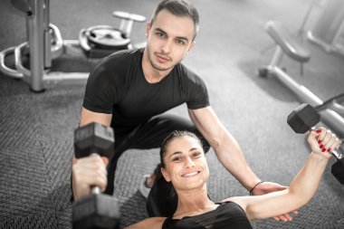 Kadın fitness antrenör yardımıyla yapıyor.