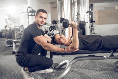Kadın fitness antrenör yardımıyla yapıyor.