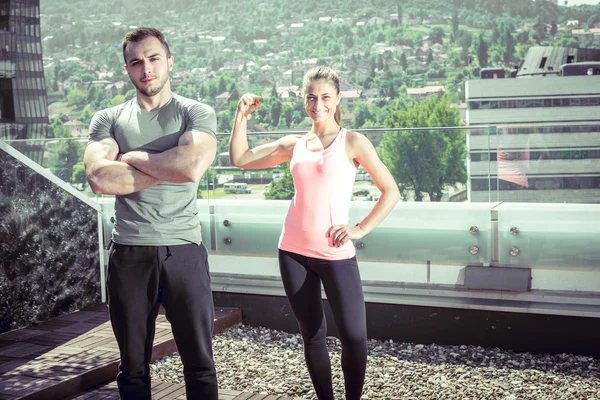Twee jonge volwassen fitness modellen poseren op dak. — Stockfoto