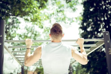 Kaslı adam pull-up egzersiz açık havada yapmak.