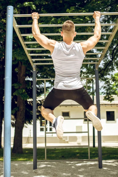 Muskularny mężczyzna robi ćwiczenia pull-up na zewnątrz. — Zdjęcie stockowe