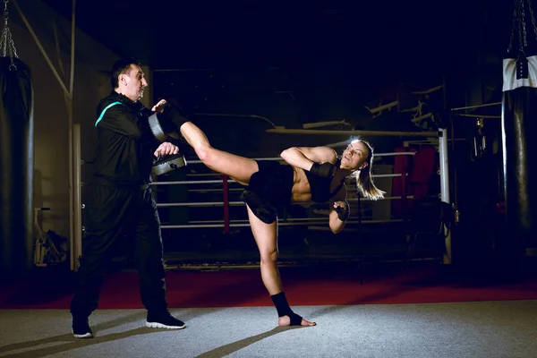 Holka kope zpět nohu během tréninku kickboxu — Stock fotografie