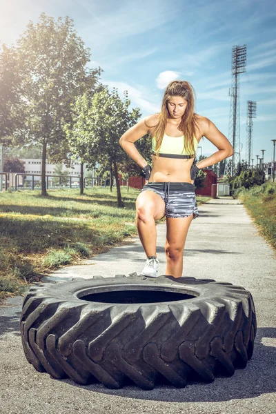 Sportovní žena školení s pneumatikou. — Stock fotografie