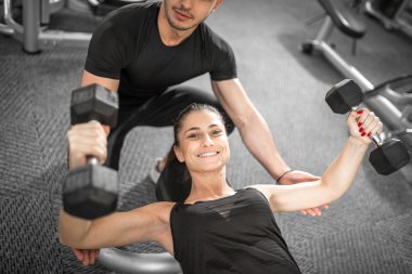 Kadın fitness antrenör yardımıyla yapıyor.