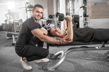Kadın fitness antrenör yardımıyla yapıyor.