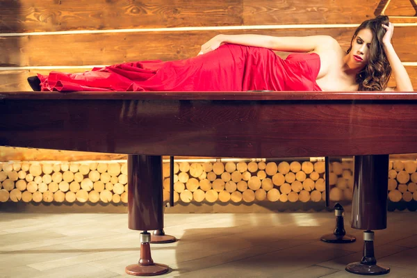 Menina vestido vermelho deitado na mesa de bilhar — Fotografia de Stock