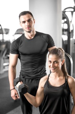 Onun kişisel antrenör ile spor salonunda pazı bukleler yapıyor kadın