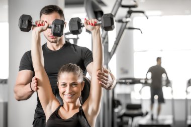 Kadın fitness antrenör yardımıyla yapıyor.