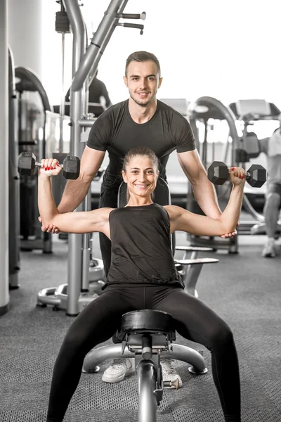 Vrouw doet fitness met persoonlijke trainer help. — Stockfoto