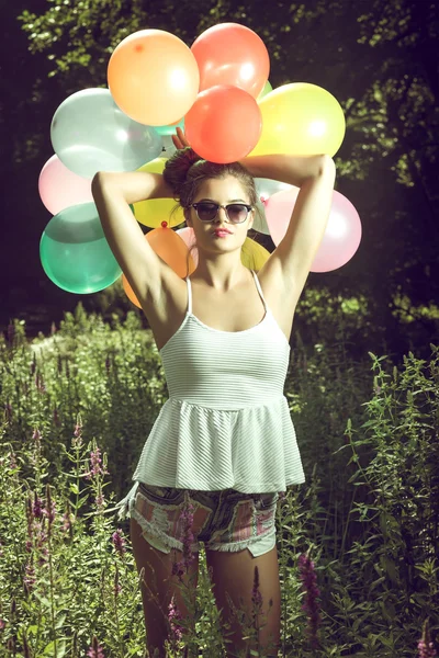 Meisje poseren met ballonnen in de natuur — Stockfoto