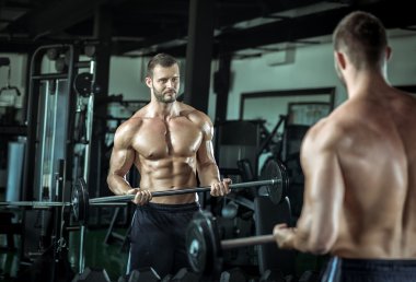 Spor salonunda ağırlık kaldıran bir adam.