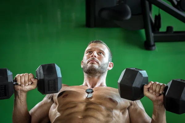 Man doing dumbbell press while lying down — Stock Photo, Image