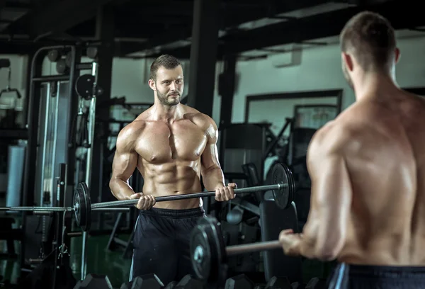 Spor salonunda ağırlık kaldıran bir adam.